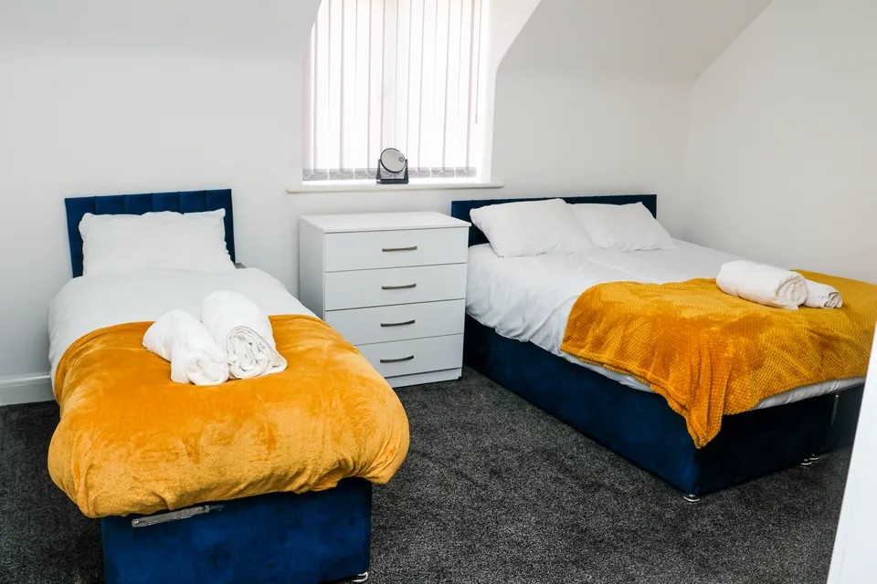 Bedroom at Humber Hub with two single beds and mustard throws