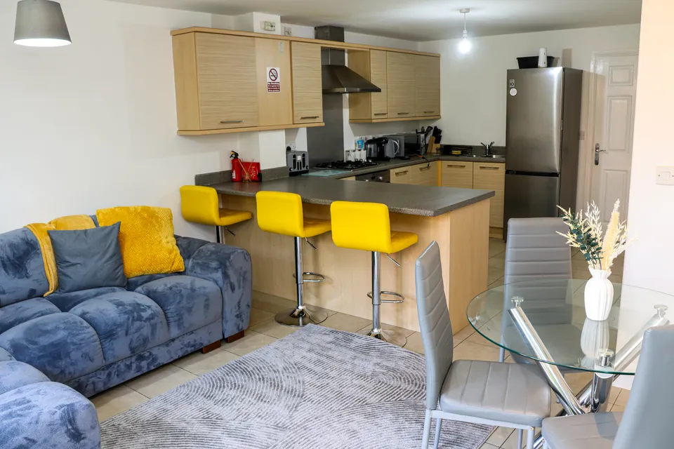 Kitchen at Humber Hub with a breakfast bar, yellow stools and a tall fridge-freezer