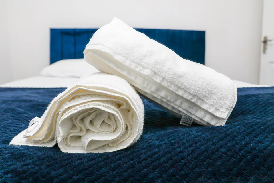 Fresh towels rolled on a navy bed at Humber Hub