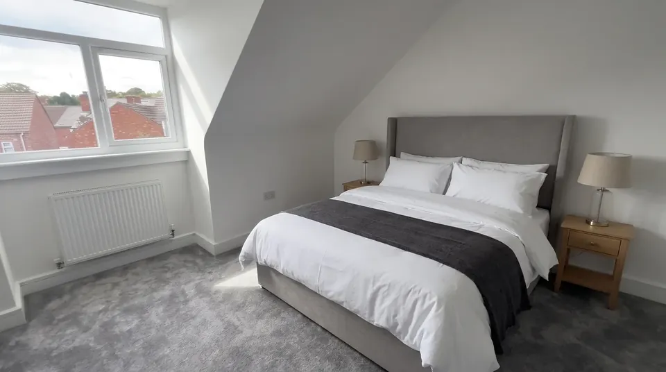 Top-floor bedroom with a king-size bed under a sloping ceiling (illustrative furnishing)