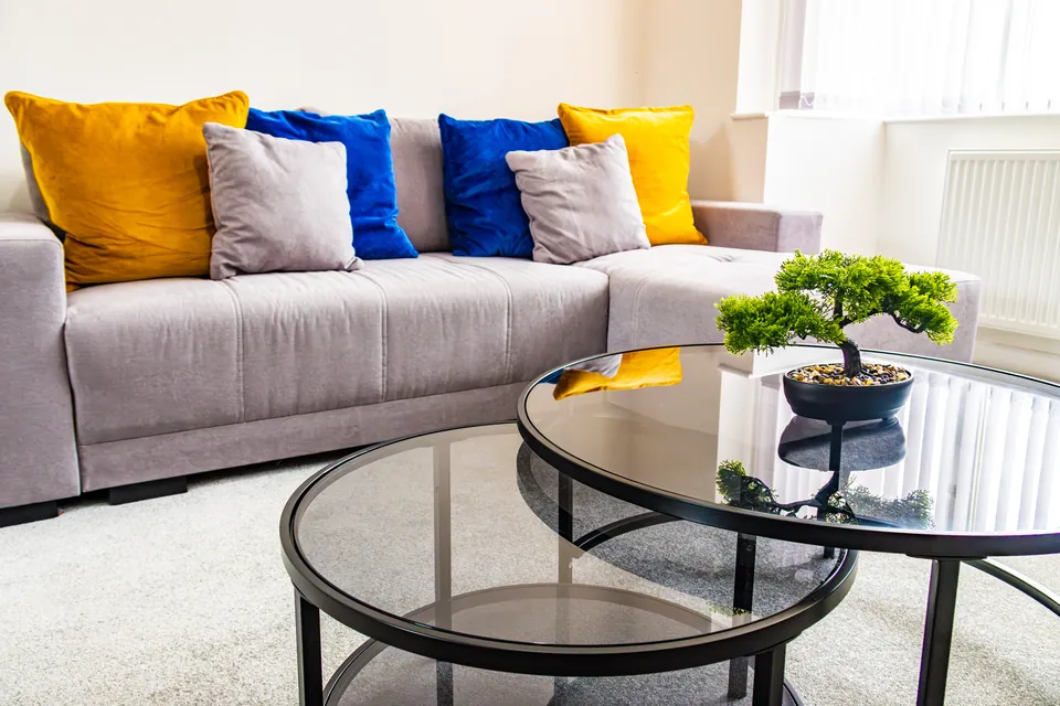 Living room at Sullivan Heights with a corner sofa, blue and mustard cushions and glass coffee tables
